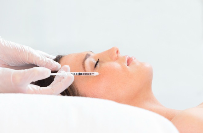 saiba porque escolher um bom profissional ao aplicar botox é essencial. mulher em mesa de profissionar a aplicar botox em seu rosto