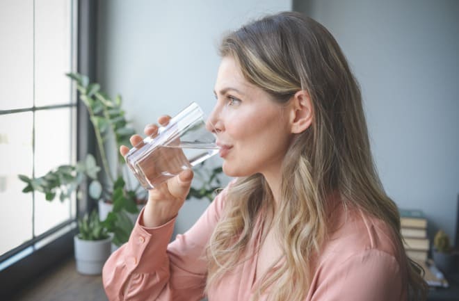 mulher se hidratando para retenção de líquido 