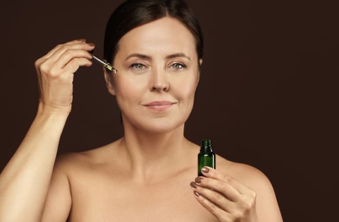 Mulher aplicando sérum facial em sua rotina de skin care após lifting cirúrgico