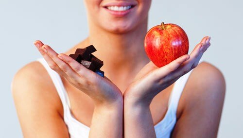 Chocolates ou Frutas de sobremesa Mulher segurando chocolate em uma mão e uma maçã em outra para manter o peso