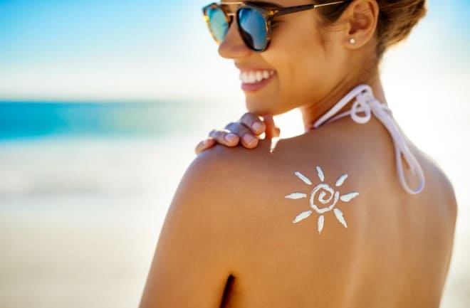 mulher usando protetor solar para manter bronzeamento em dia