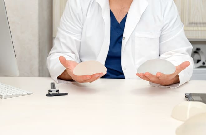 médico mostrando duas opções de prótese de mama